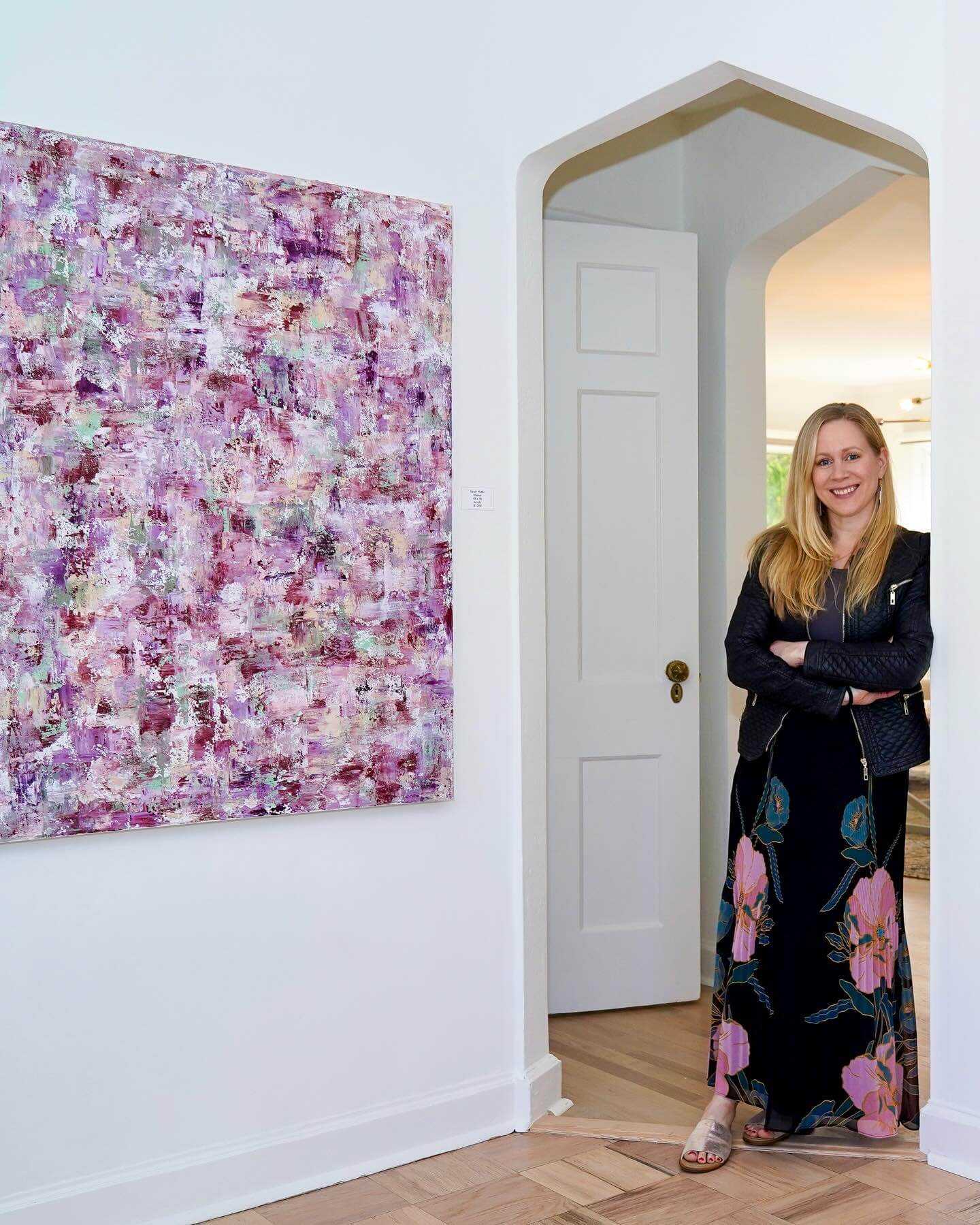 Woman standing in a doorway with a pink floral painting on the wall.