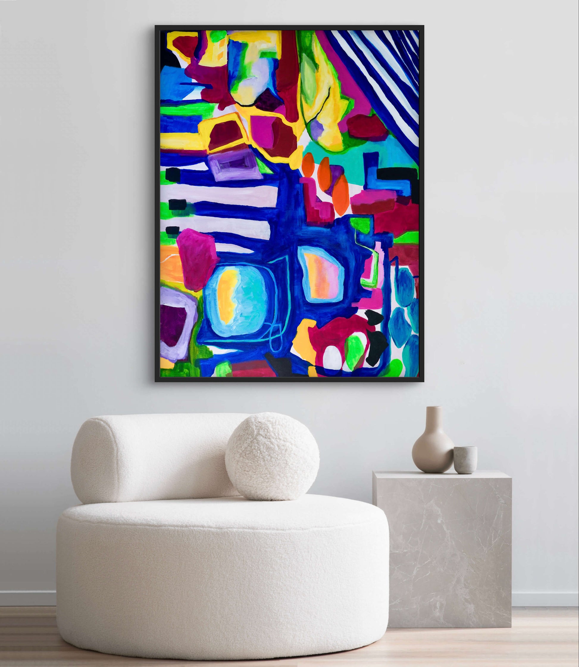 Colorful abstract painting on a wall above a white chair.