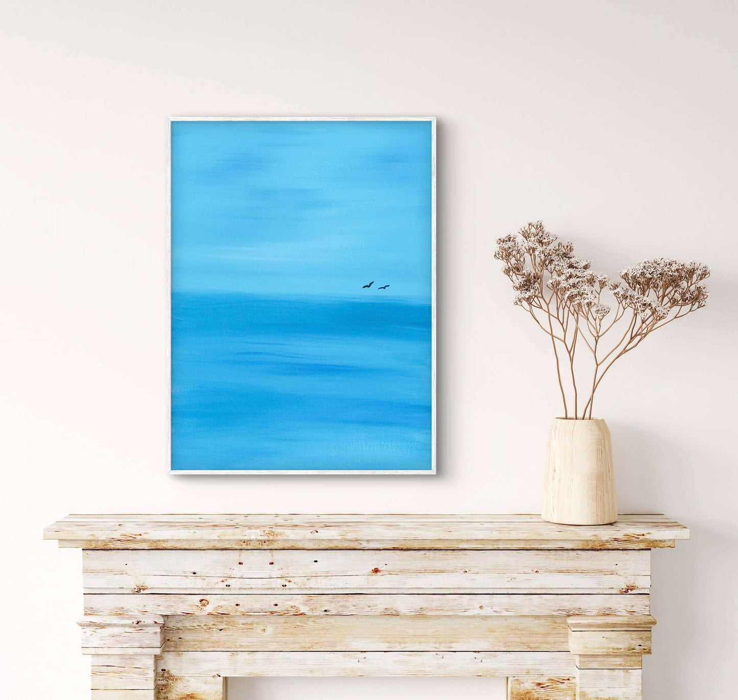 Framed artwork of a blue sky with a bird on a wooden shelf.